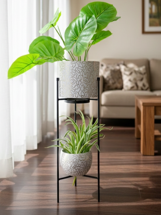Two potted plants on a black metal plant stand in a living room setting.