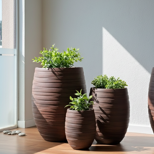 Three brown textured planters with green plants on a wooden floor.