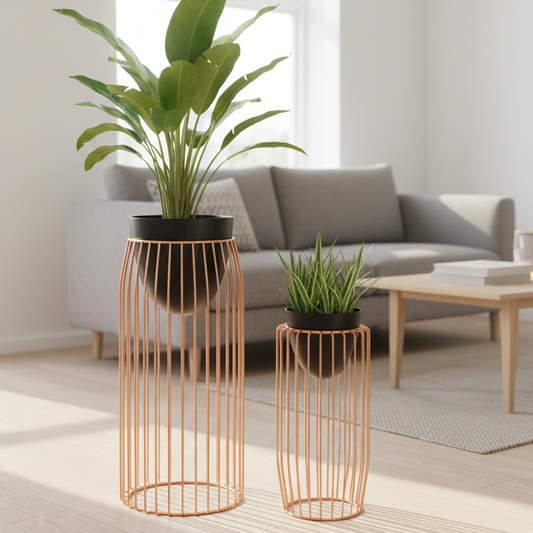 Two copper wire plant stands with black pots containing green plants on a white background