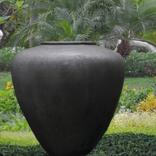 Large black vase in a garden setting with greenery and flowers.