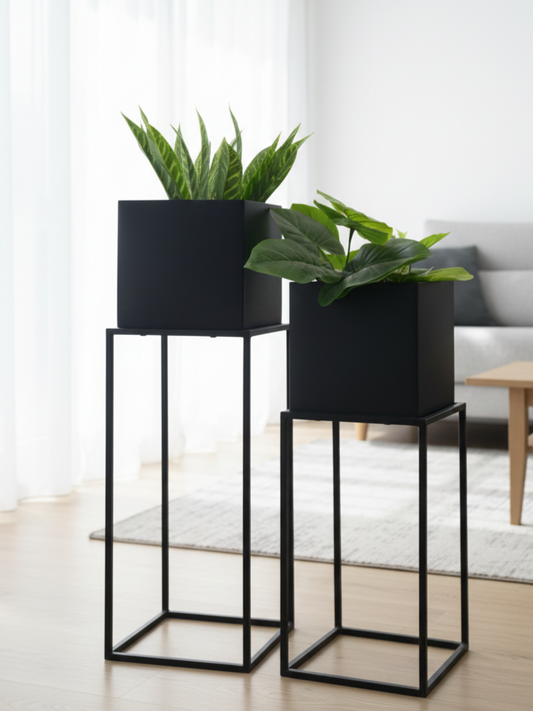Two black planters with green plants on stands in a room.