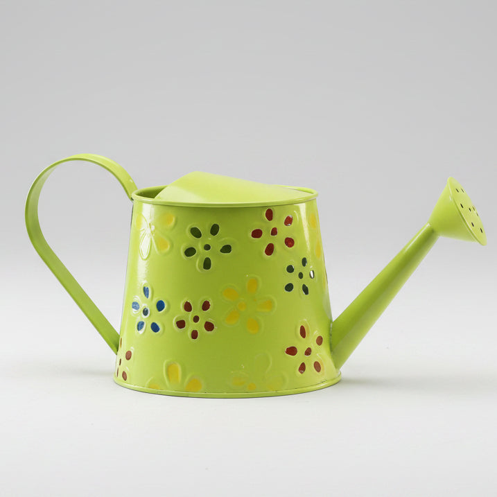 Green watering can with decorative holes on a white surface