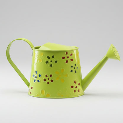 Green watering can with decorative holes on a white surface