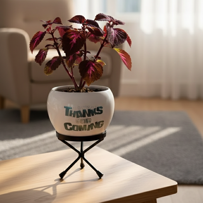 Potted plant on a table with 'Thanks are Coming' message in a bright room.