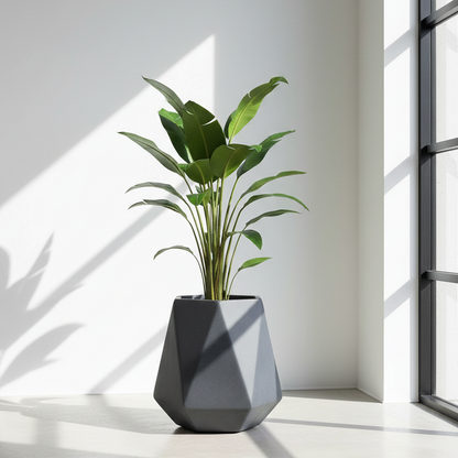 Geometric gray planter with a green plant on a light wooden floor with a white wall and window in the background.