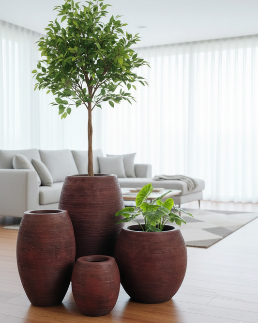 Set of brown ceramic planters with plants on a wooden floor in a living room.