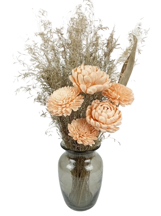Bouquet of peach-colored flowers and dried elements in a gray vase on a light background