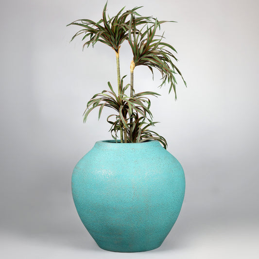 Turquoise vase with a plant on a light gray background