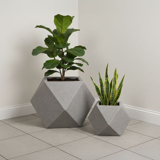Two geometric concrete planters with plants on a tiled floor against a plain wall.