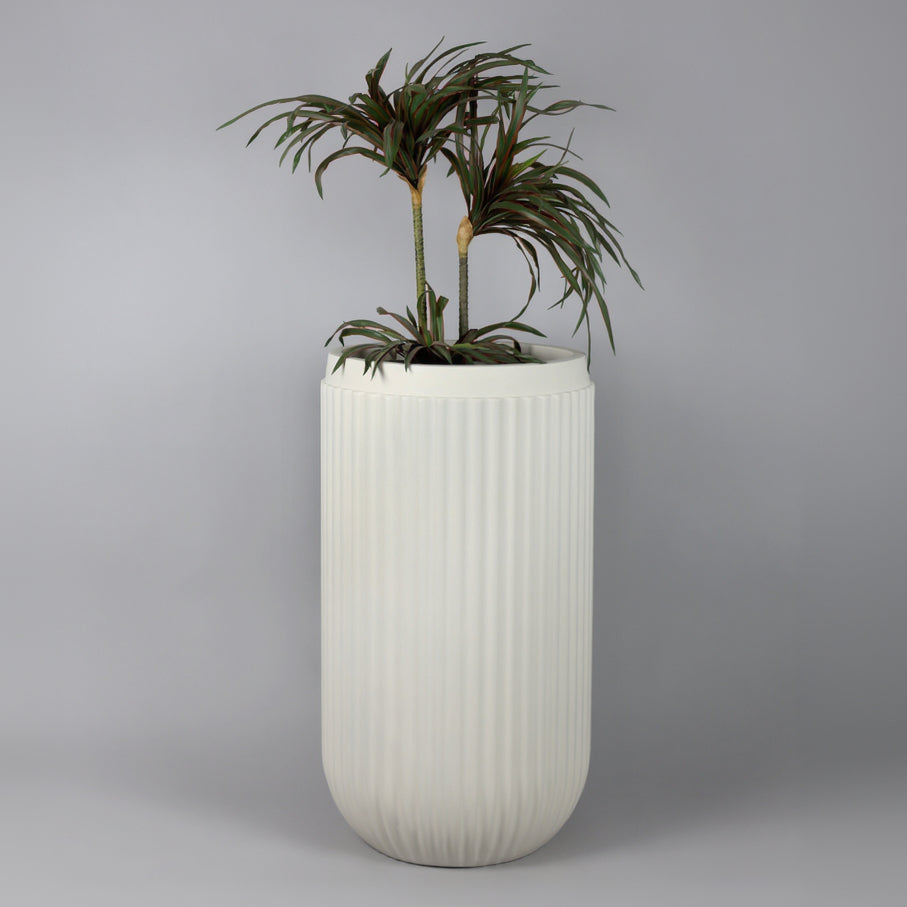 White ribbed planter with a plant on a gray background