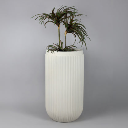 White ribbed planter with a plant on a gray background